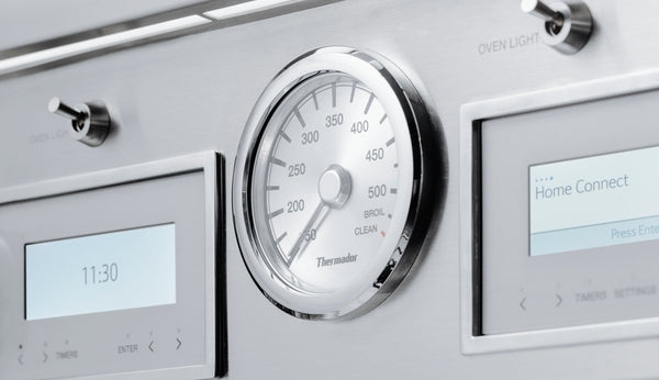 Stainless steel control panel with analog oven thermometer and digital displays for temperature and timer in Thermador ranges collection