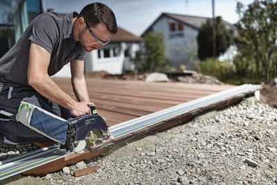 Man using a power saw with Festool guide rail connectors for precise woodworking on an outdoor decking project