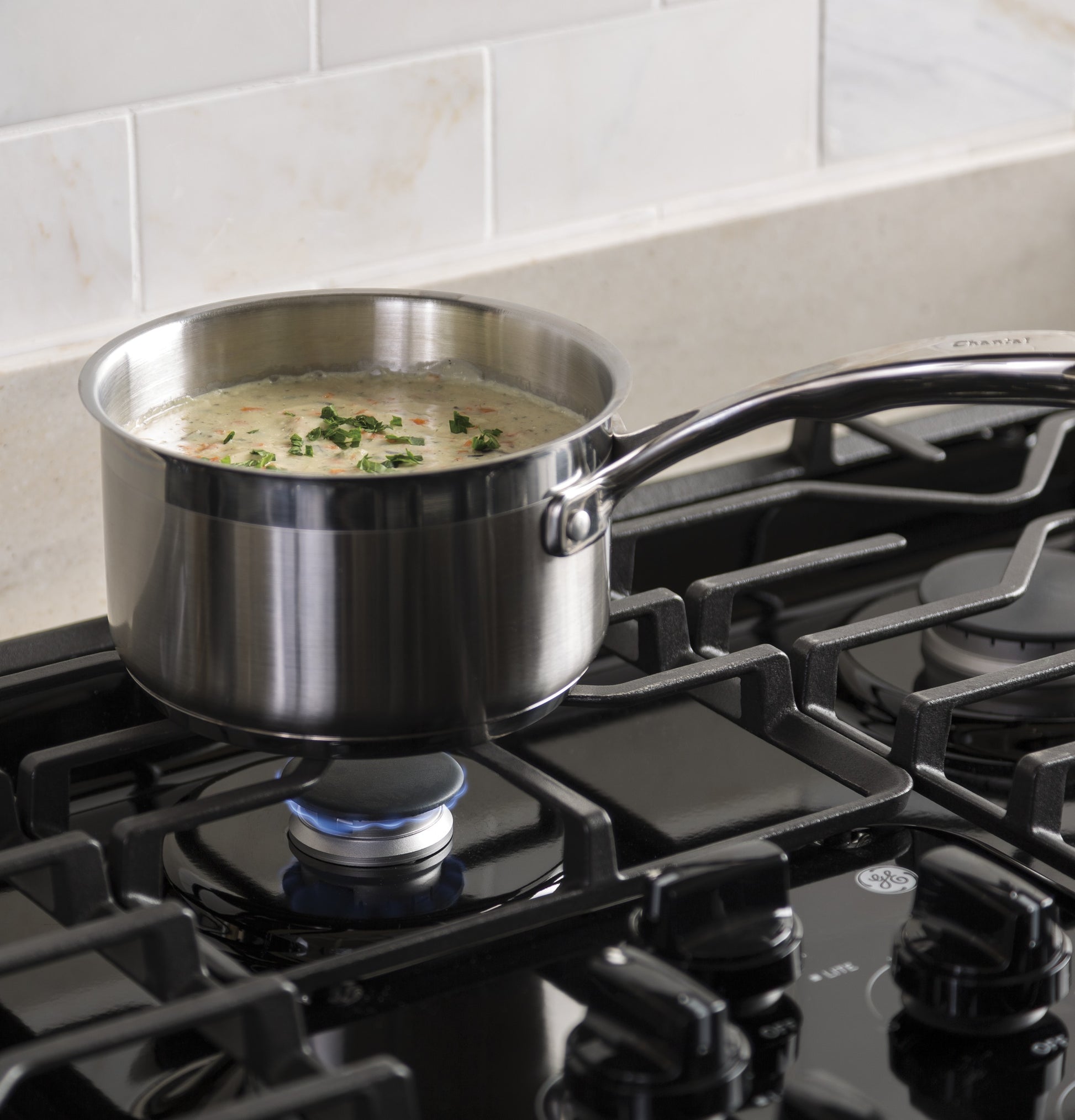 Stainless steel saucepan simmering creamy soup on a burner of a built-in gas cooktop in Kitchen & Kitchenware collections