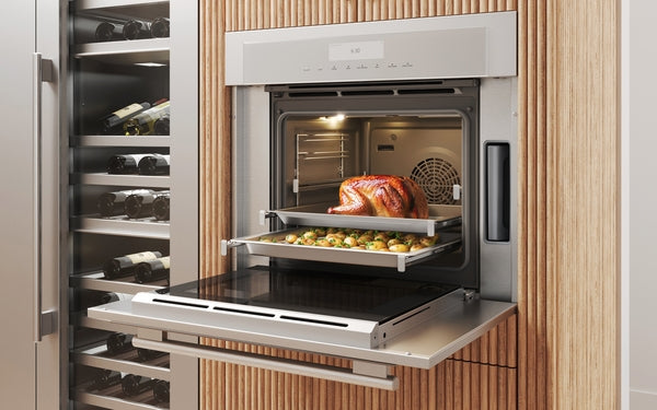 Stainless steel wall oven baking whole turkey with vegetables in modern kitchen surrounded by wine storage units