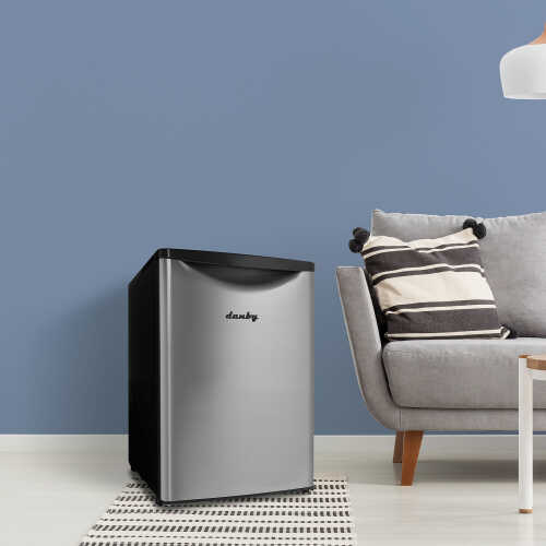 Compact stainless steel mini refrigerator with black top handle in a contemporary living space from Appliances collection