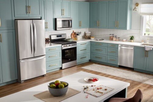 Modern kitchen with stainless steel refrigerator, gas range, dishwasher, and microwave surrounded by light blue cabinetry