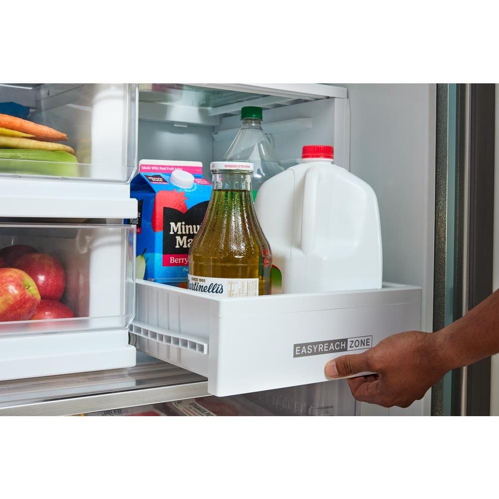 Hand pulling out bottom freezer drawer with beverages and milk inside a Whirlpool French door refrigerator.