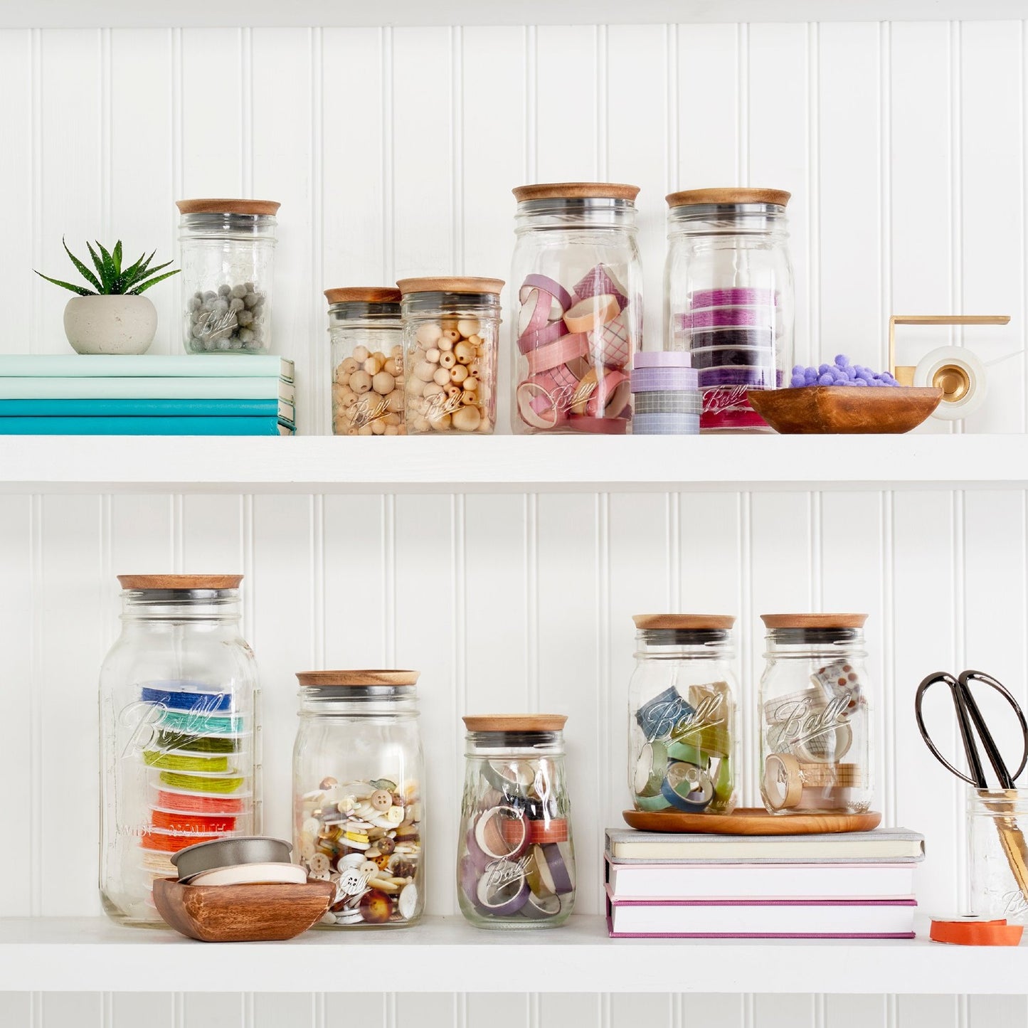 Clear glass jars with wooden lids storing craft supplies on white shelves in kitchenware and kitchen gadgets collections