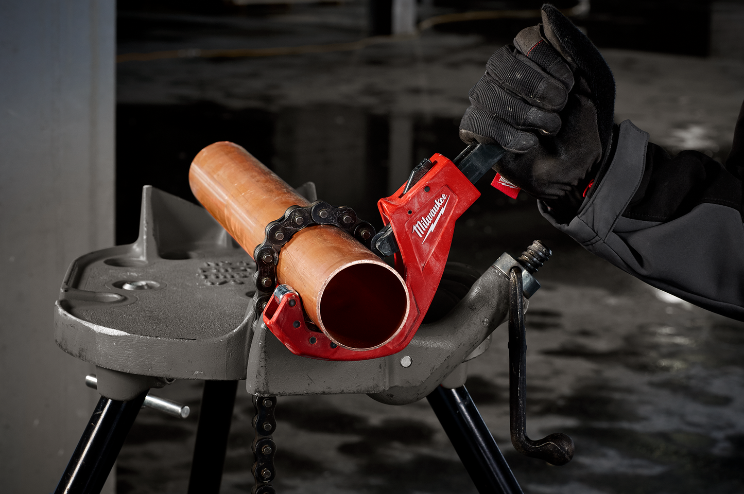 Red Milwaukee quick adjust tubing cutter gripping copper pipe with gloved hand for home improvement use