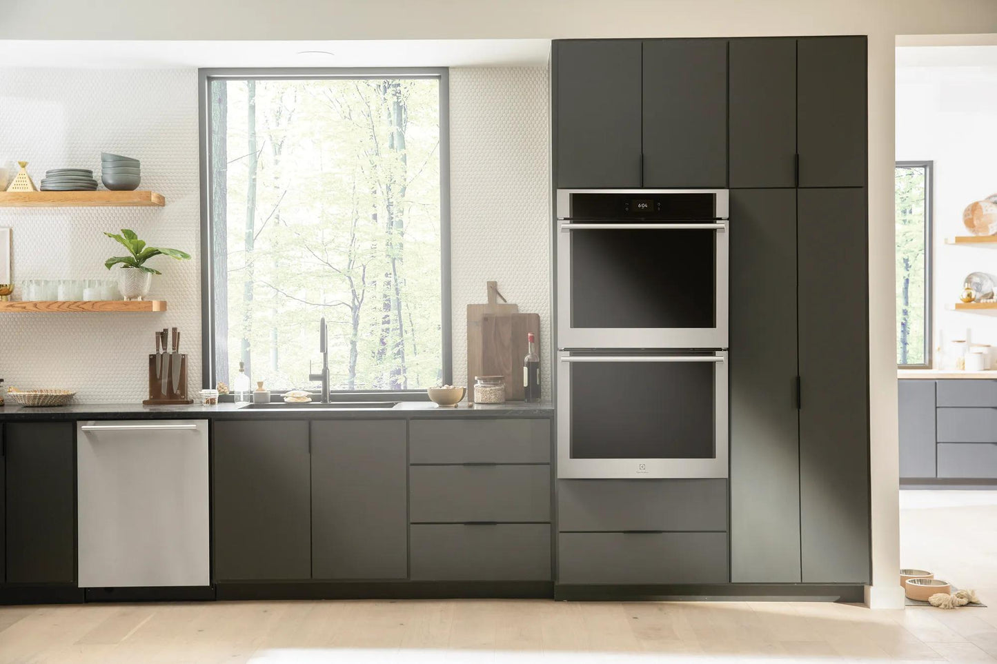 Built-in stainless steel electric double wall oven with digital controls in modern kitchen with dark cabinetry