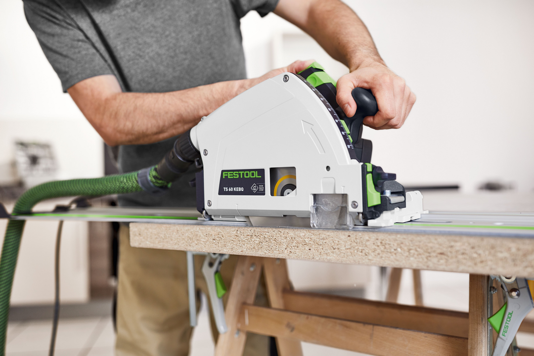 Person operating Festool TS 60 KEB-F plunge cut track saw on wood panel for precise cutting in power tools collection
