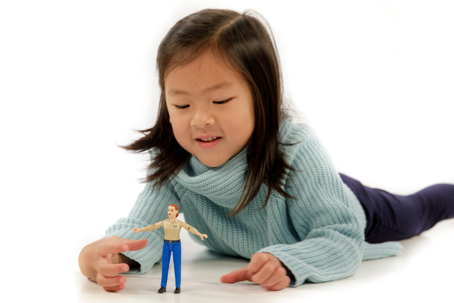 Young girl playing with lifelike bruder figure wearing blue jeans and beige shirt from toys and games collection