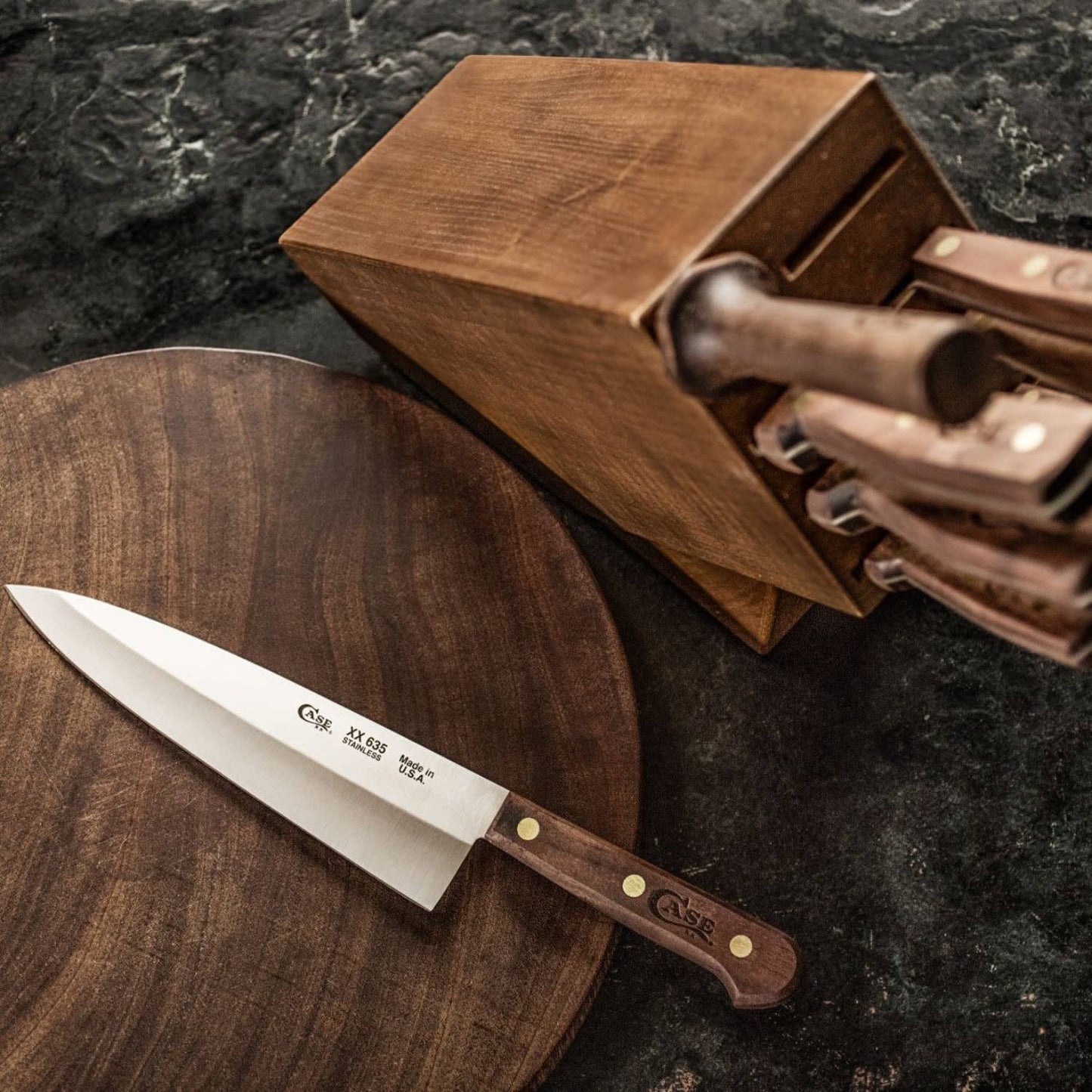 Set of kitchen knives with wooden handles in a matching wooden block on dark countertop in kitchenware collections