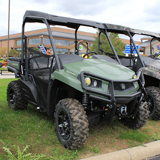 Green mid-size utility vehicle with front brush guard and rugged off-road tires for outdoor utility use