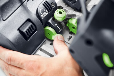 Close-up of hand adjusting green power dial on Festool plunge cut track saw for precise control in power tools collection