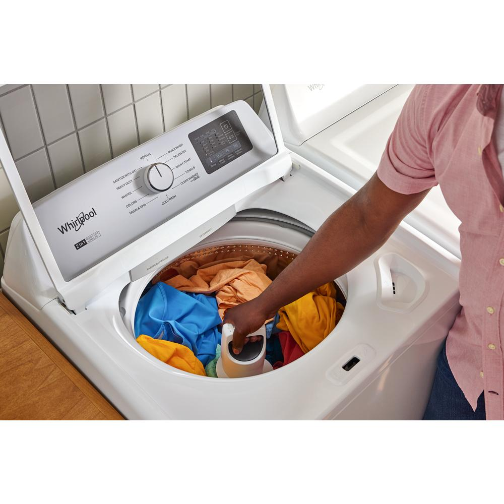 Person loading colorful clothes into a white top load washer with removable agitator from washers & dryers collection