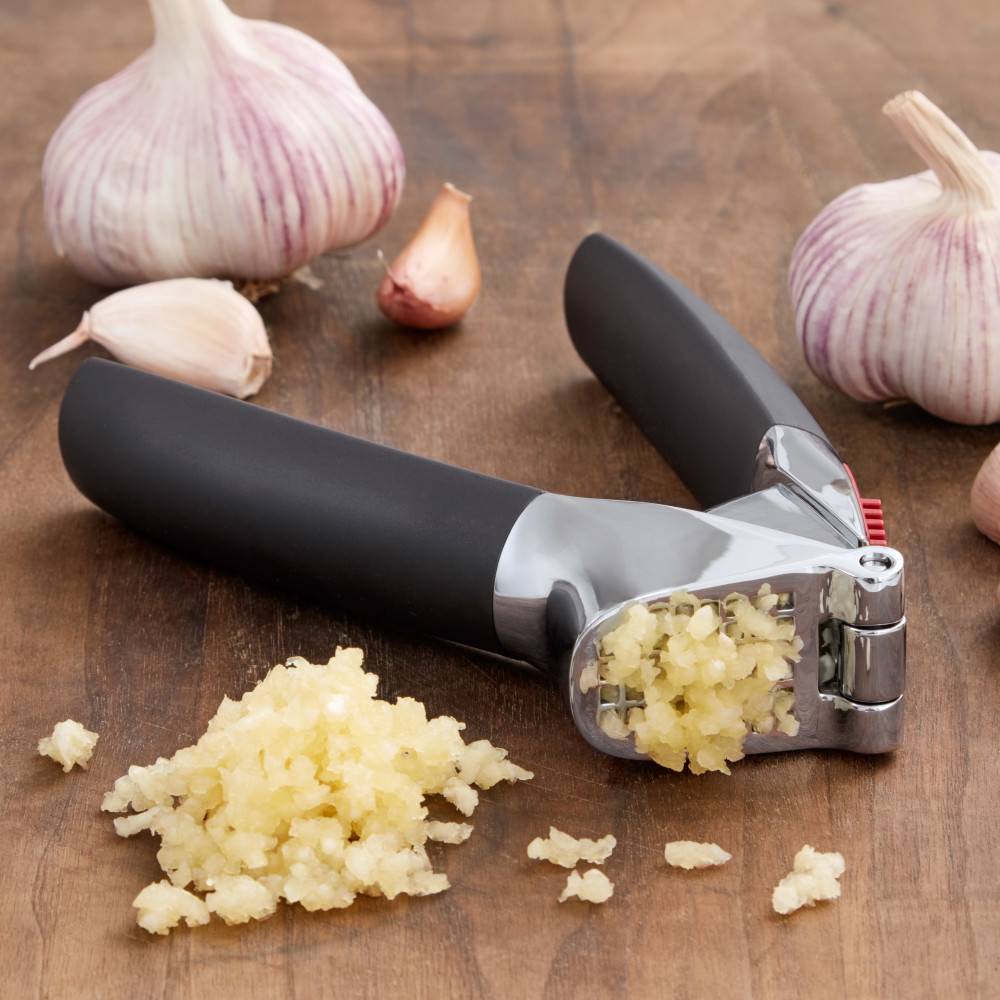Black-handled garlic press crushing fresh garlic cloves for kitchenware and home use under $50 collections