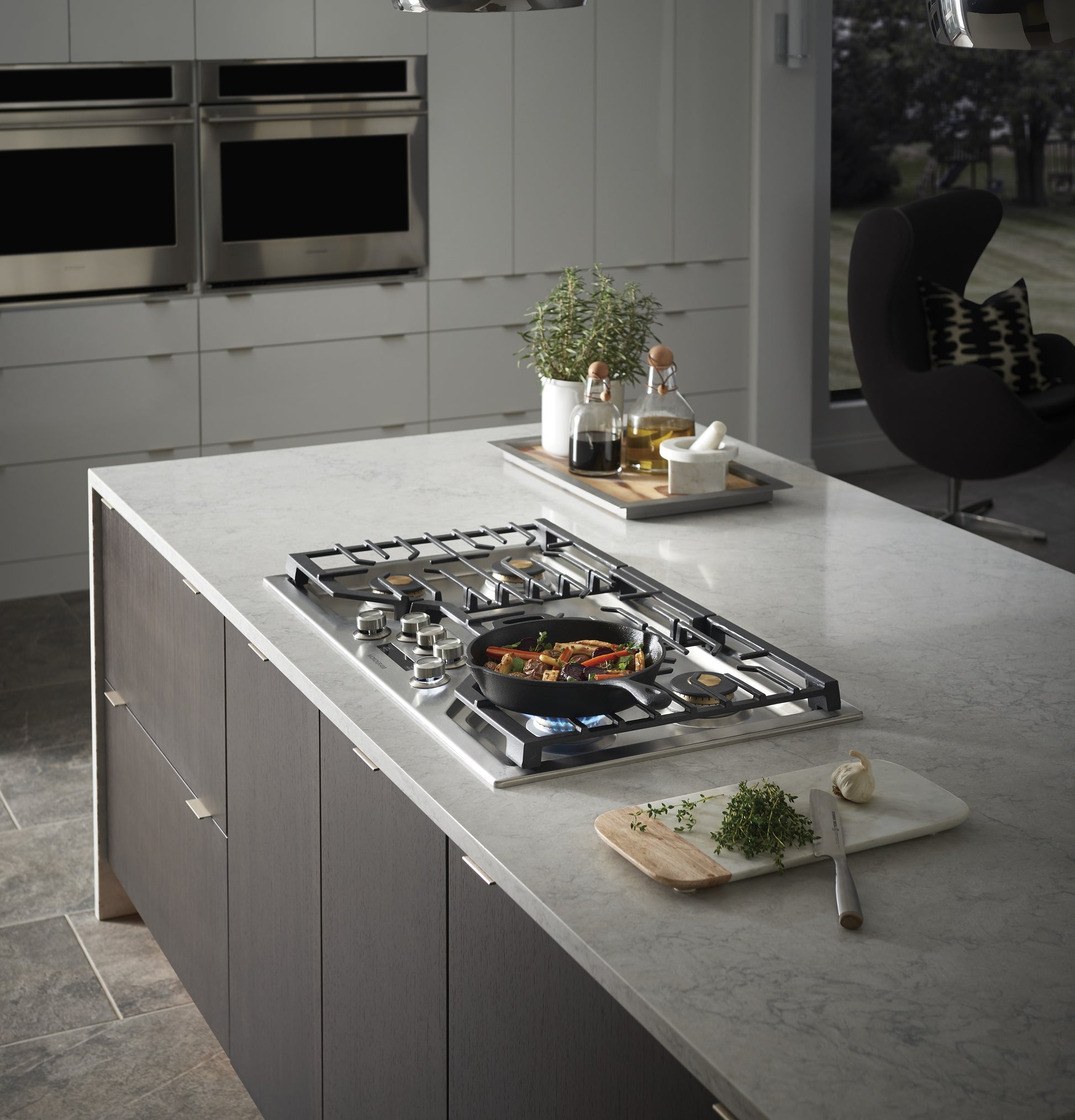 Deep-recessed gas cooktop with stainless steel surface and brass burner caps in modern kitchenware and appliance setting