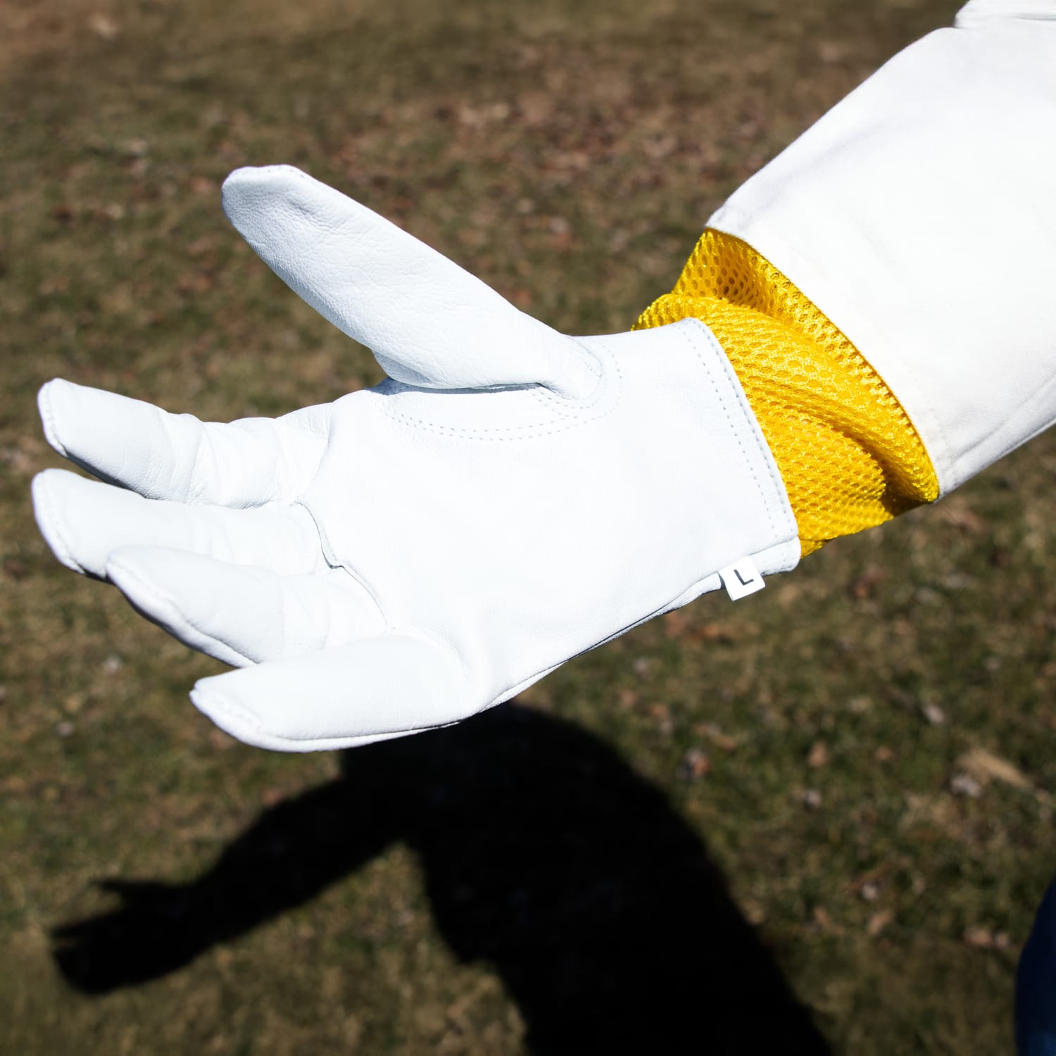 White goatskin glove with yellow mesh cuff designed for protection in beekeeping and outdoor home improvement tasks
