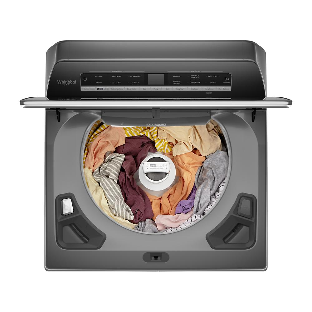 Top view of gray top load washer with digital control panel and removable agitator filled with mixed laundry