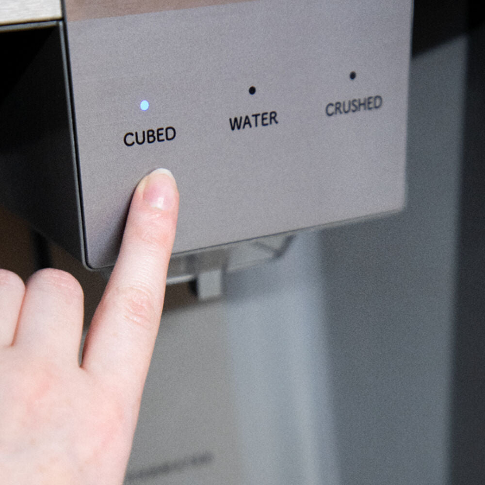 Finger pressing cubed ice selection button on stainless steel refrigerator dispenser in kitchen appliances collection