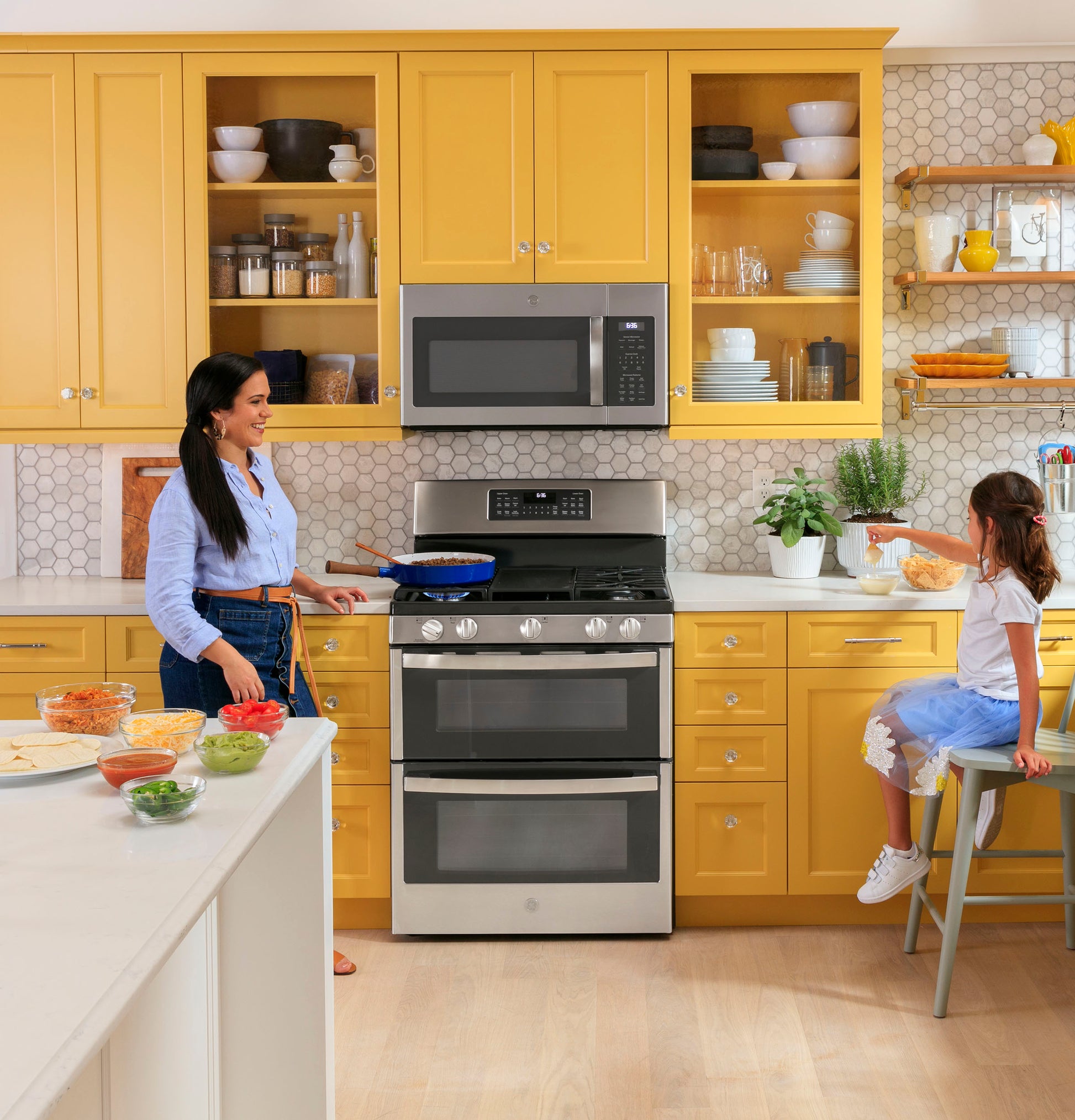 Modern kitchen with yellow cabinets featuring fingerprint resistant sensor microwave above stainless steel range and oven