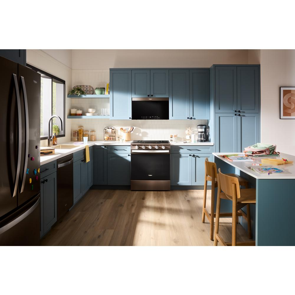 Modern kitchen featuring black air fry over-the-range microwave with blue cabinetry and wooden floor in appliance setting