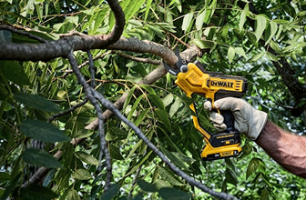 Yellow and black cordless pruning tool cutting a tree branch for home improvement and gardening tasks