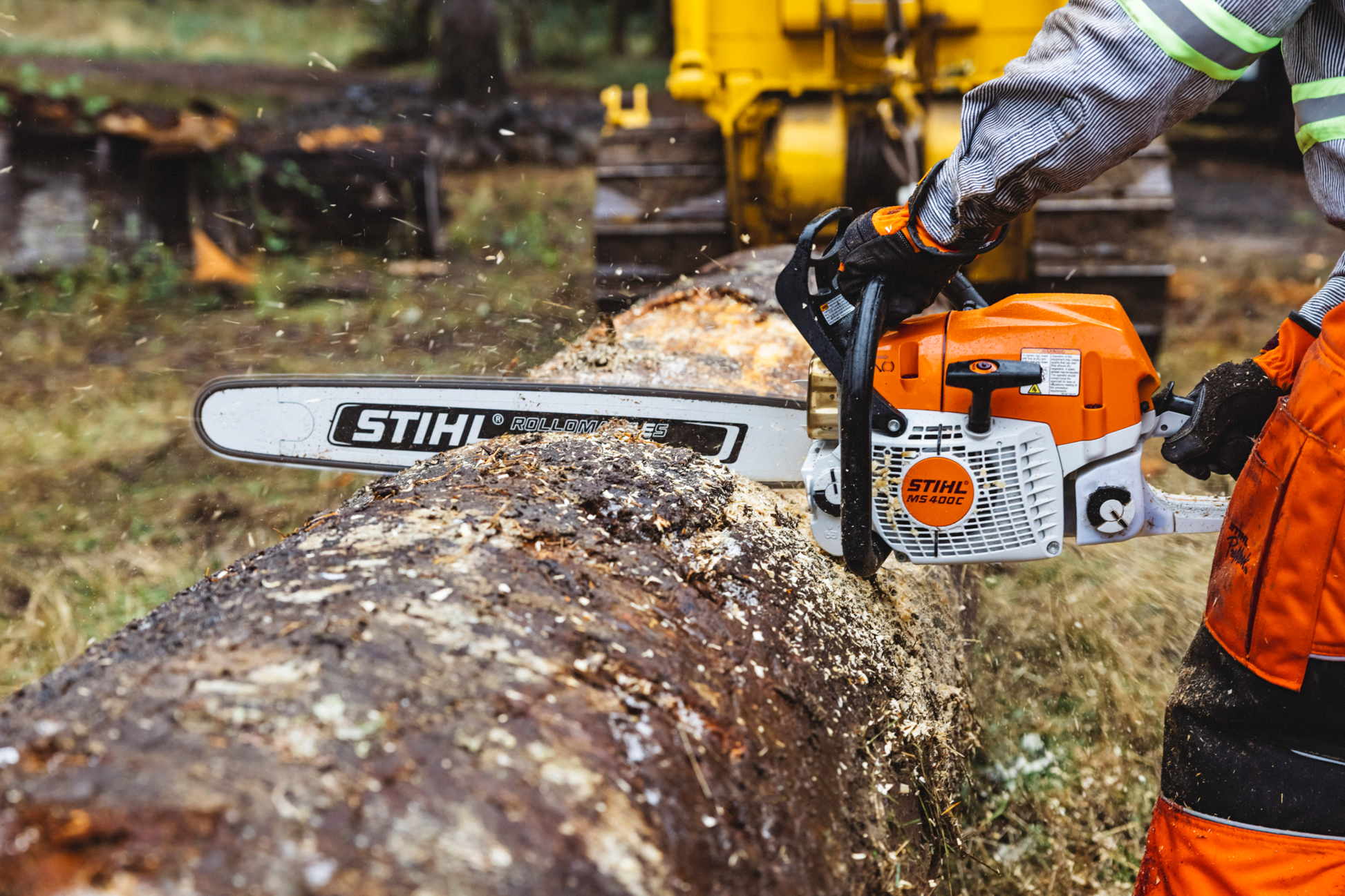 Orange and white STIHL chainsaw cutting large log outdoors with magnesium piston for tools and home improvement use