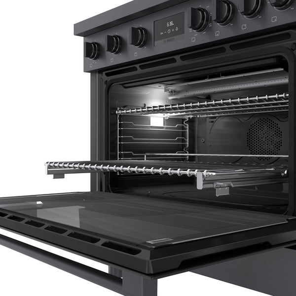 Open black stainless steel dual fuel oven with metal racks and convection fan inside modern kitchen appliance collection