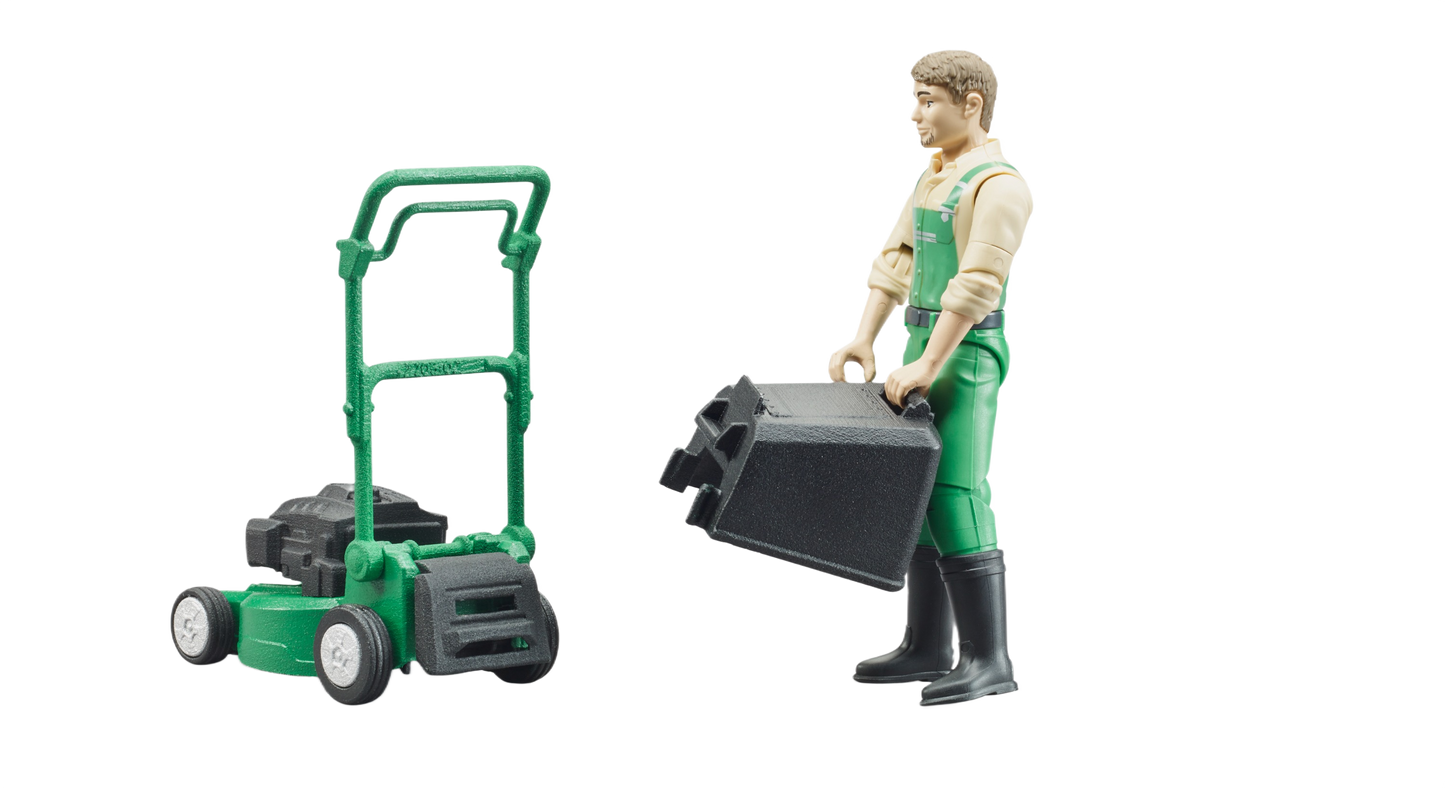 Figure in green dungarees holding grass box next to green push mower toy in Bruder Toys and under $50 collections