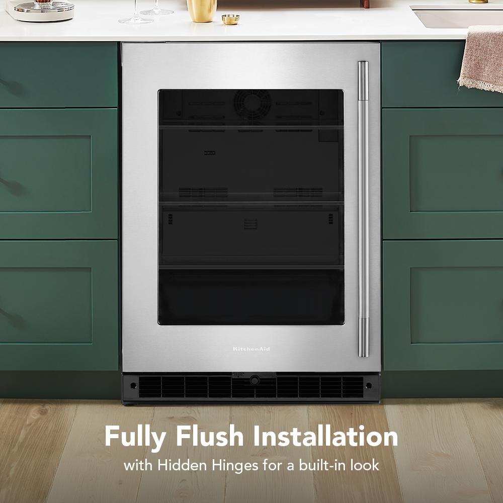 Stainless steel undercounter refrigerator with glass door integrated flush into green kitchen cabinetry and wood floor