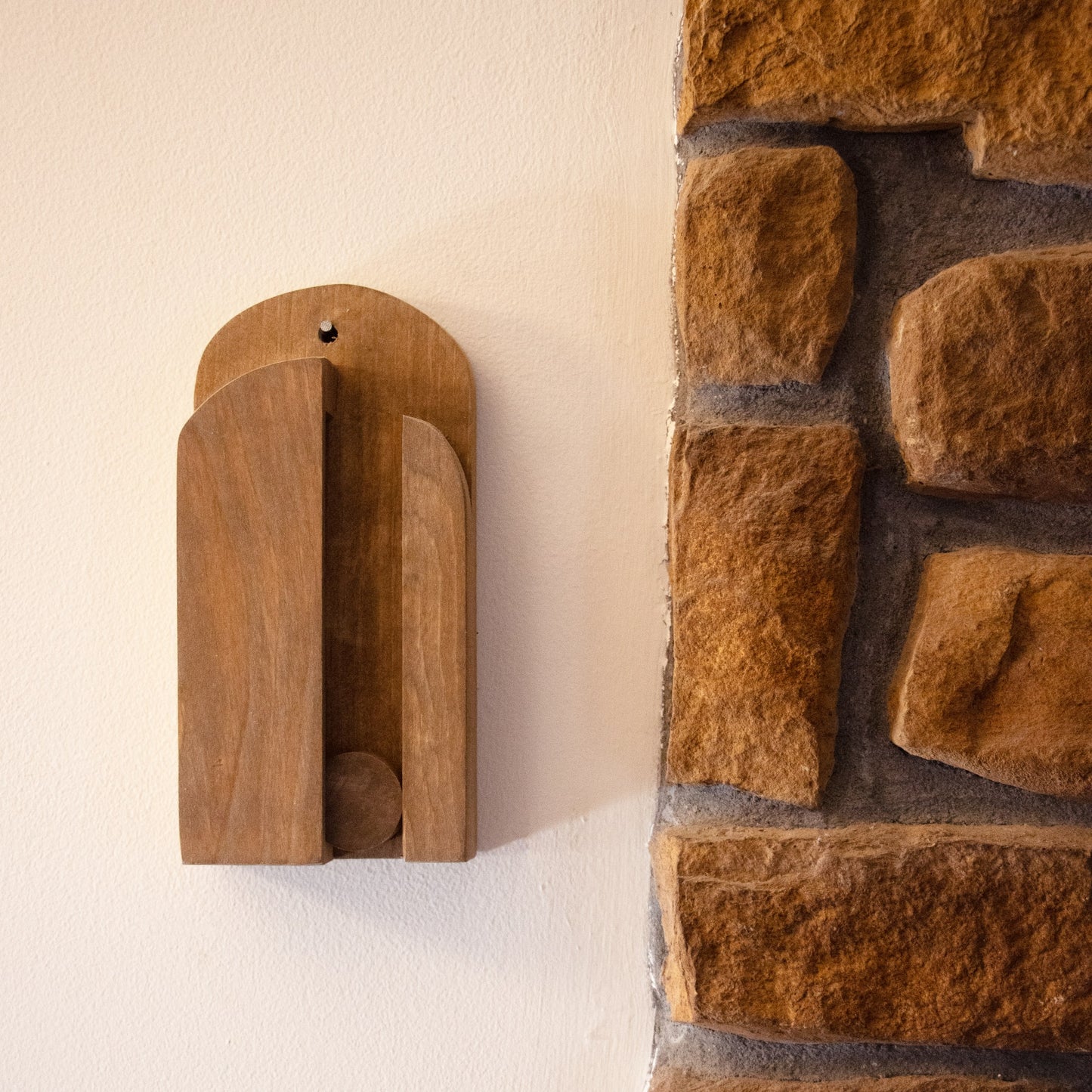 Simple handcrafted wooden broom holder mounted on wall beside rustic stonework for cleaning tools under $50 collection
