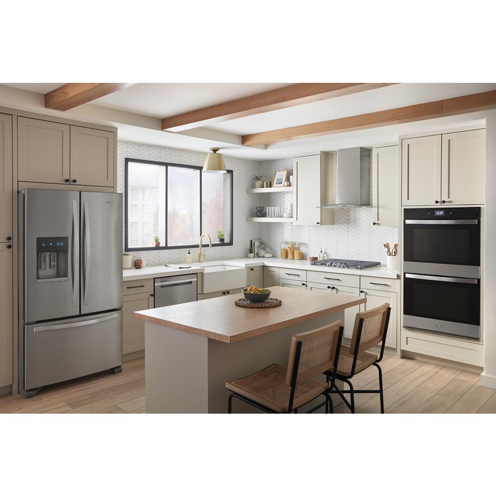 Bright modern kitchen with stainless steel refrigerator, double smart wall oven, and central island with seating in appliances collection