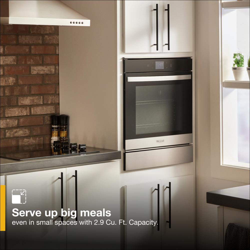 Built-in stainless steel convection wall oven integrated into a modern kitchen with white cabinetry and brick backsplash