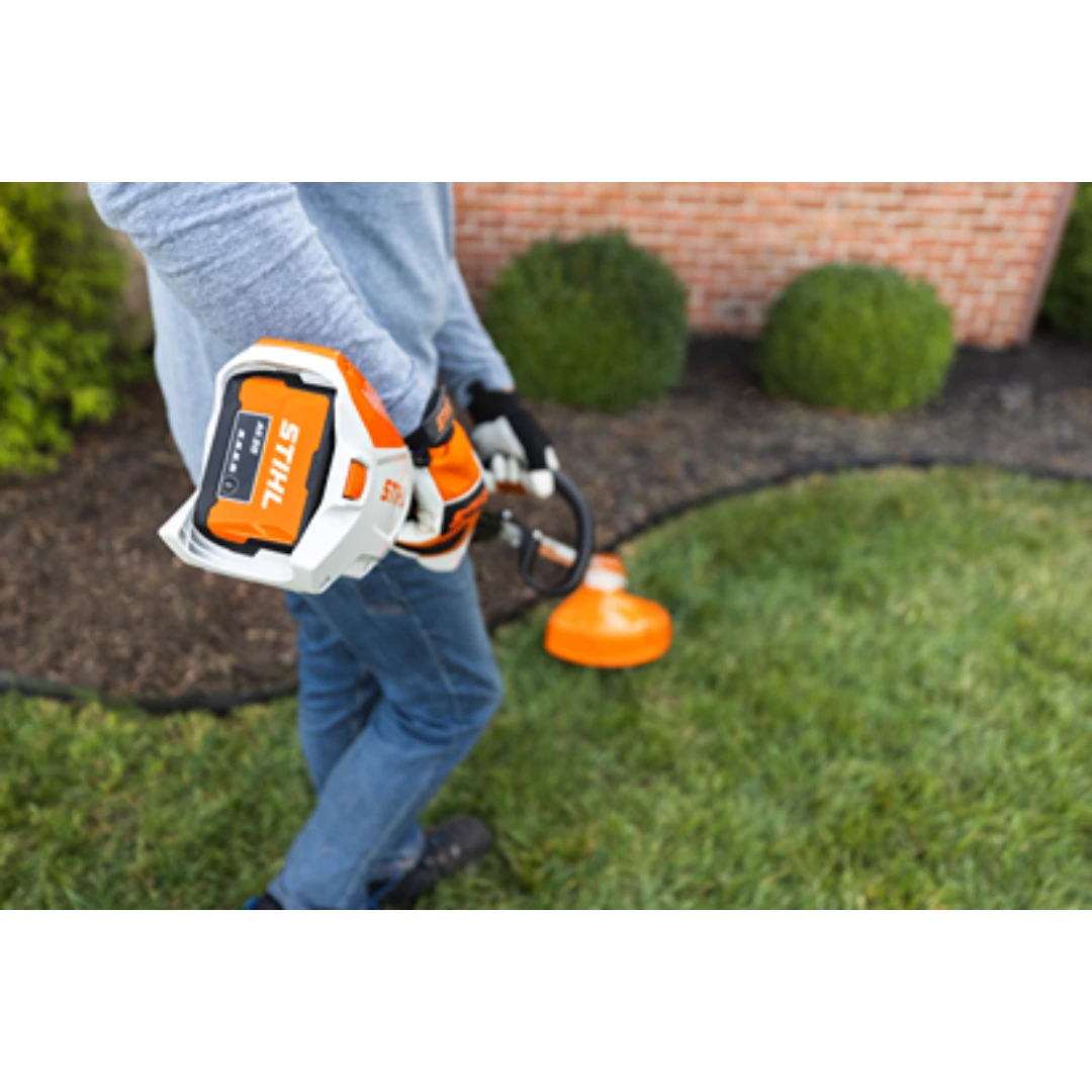 Person using orange and white battery-powered trimmer with adjustable handle for lawn edging in home improvement tasks