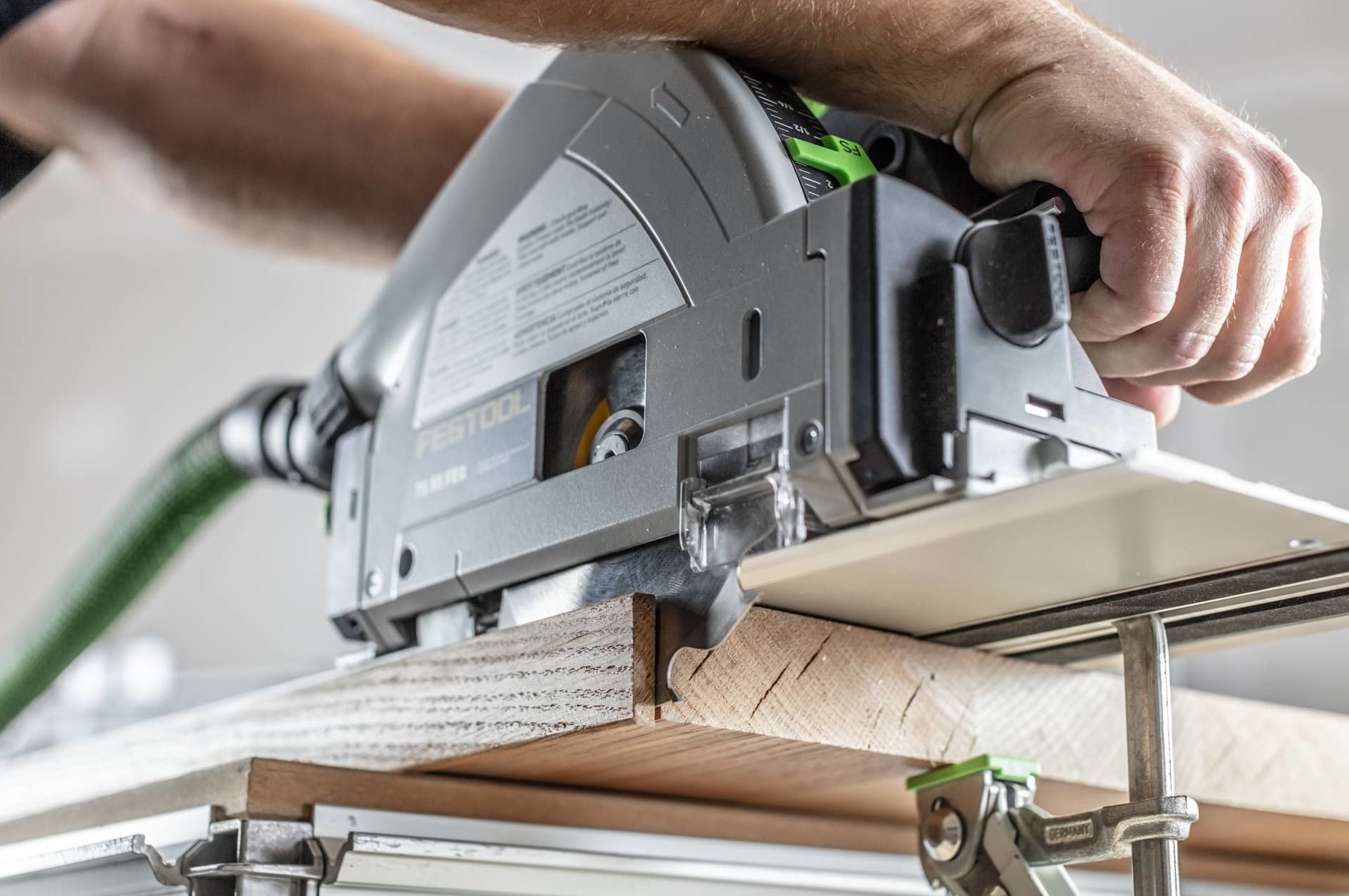 Person using Festool plunge-cut track saw on wood with guide rail for precise home improvement cuts