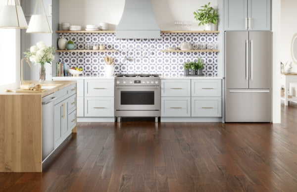 Modern kitchen with stainless steel appliances, white cabinetry, hardwood floors, and patterned tile backsplash in home improvement setting