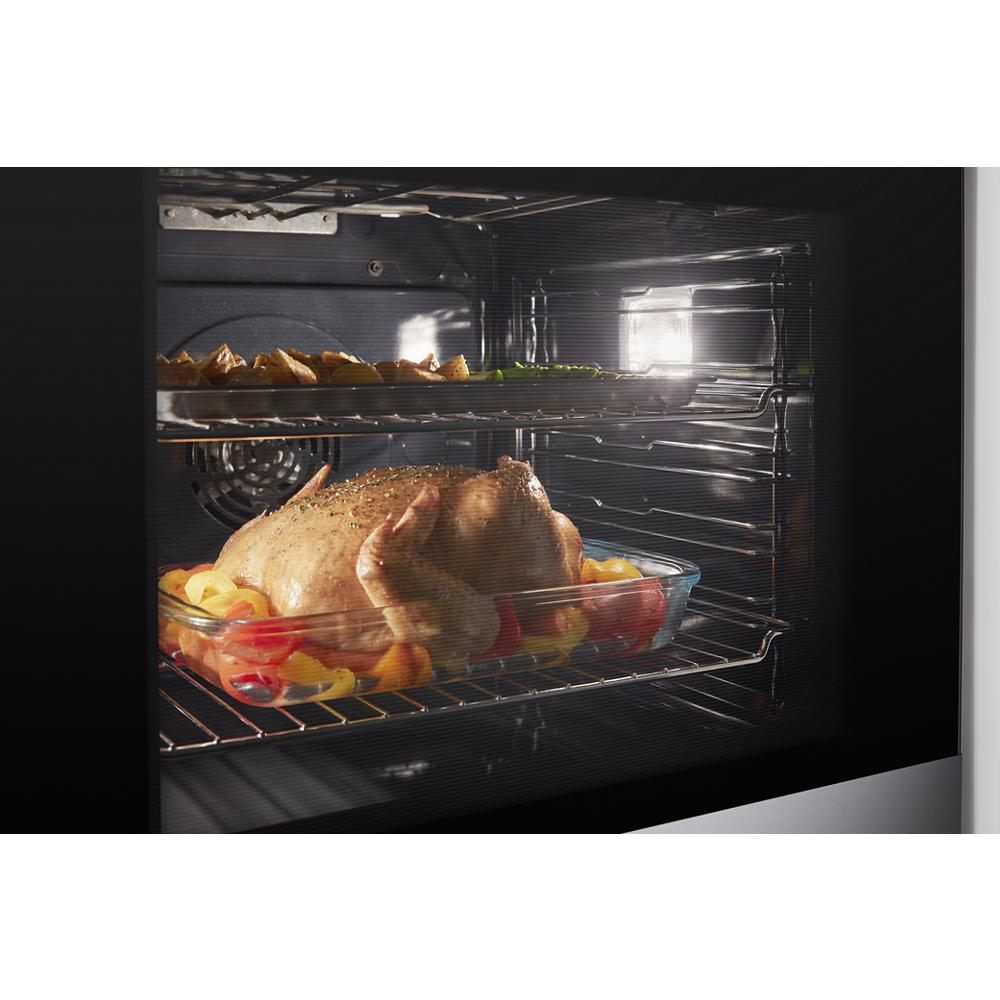 Roast chicken and vegetables cooking inside a stainless steel convection kitchen wall oven from appliances collection