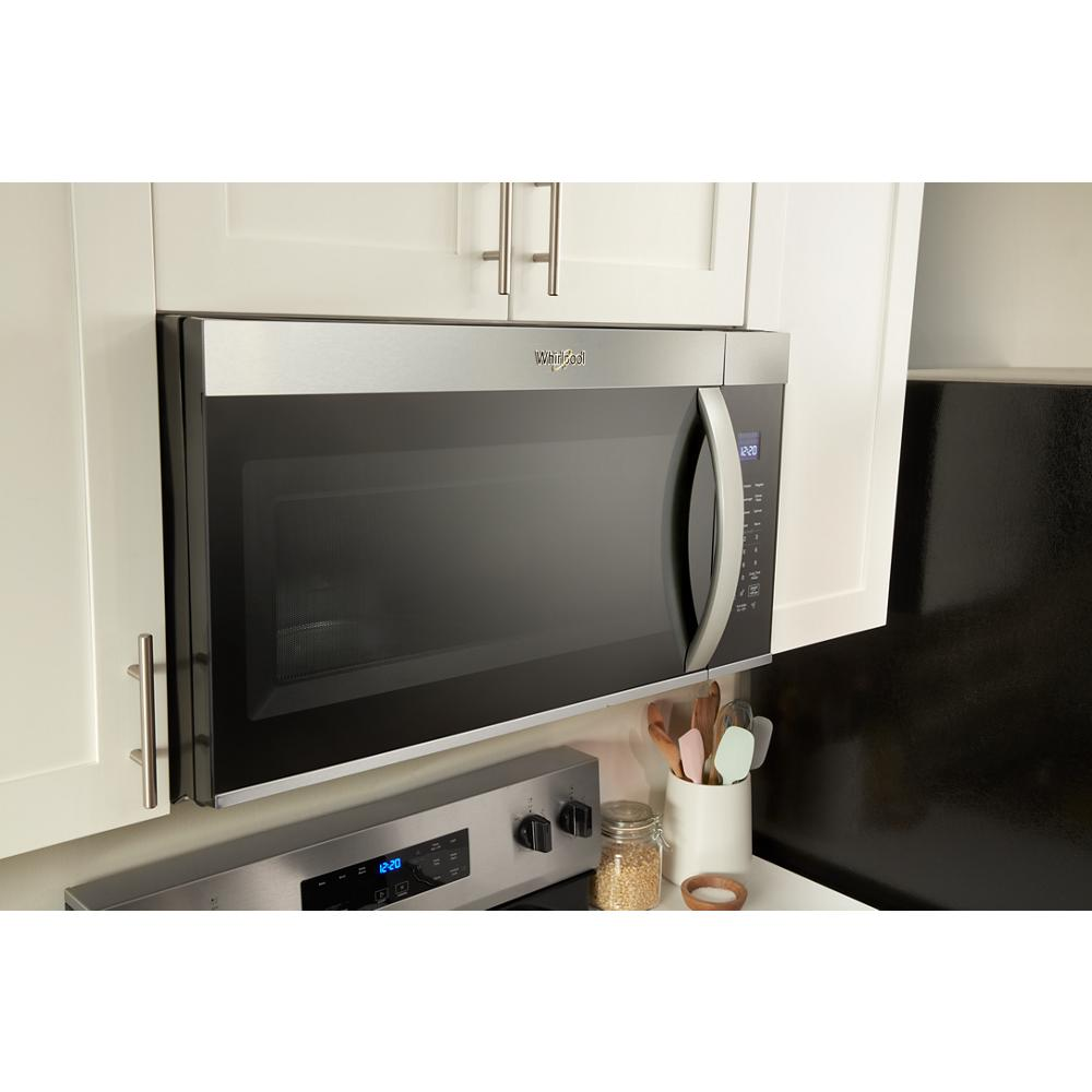Over-the-range stainless steel microwave with digital display installed above electric range in modern kitchen setup