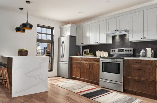 Modern kitchen with stainless steel slide-out range hood, stove, refrigerator, dark wood lower cabinets, and white upper cabinets