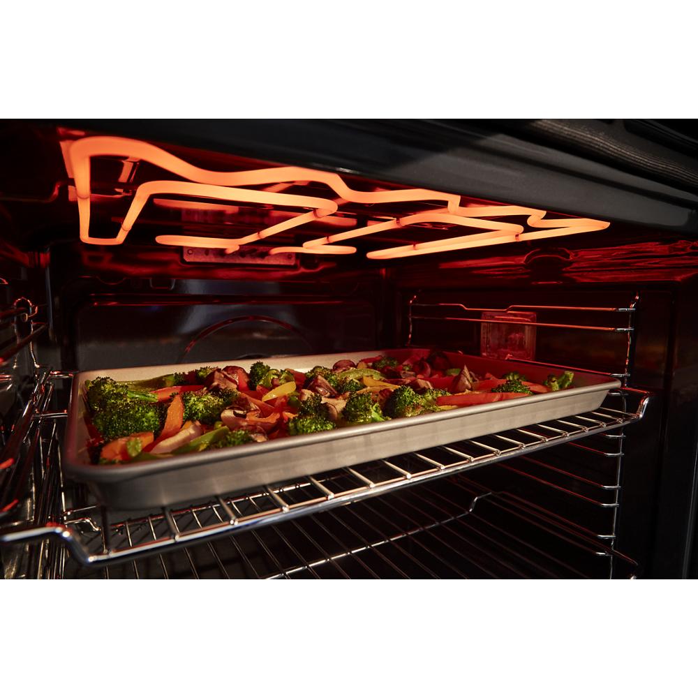 Tray of mixed vegetables roasting under glowing heating elements inside a wall oven from Kitchen & Kitchenware collection