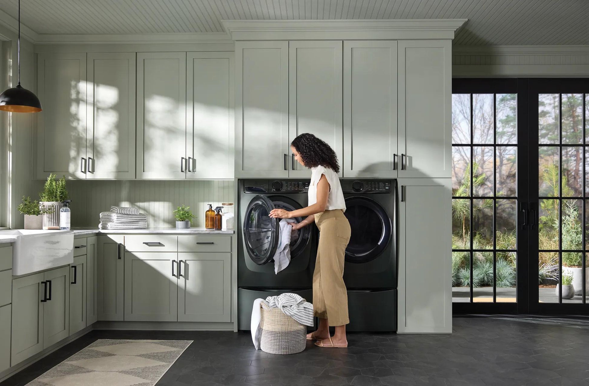 Woman loading dark gray front load washer with digital controls in light green laundry room from front load washers collection