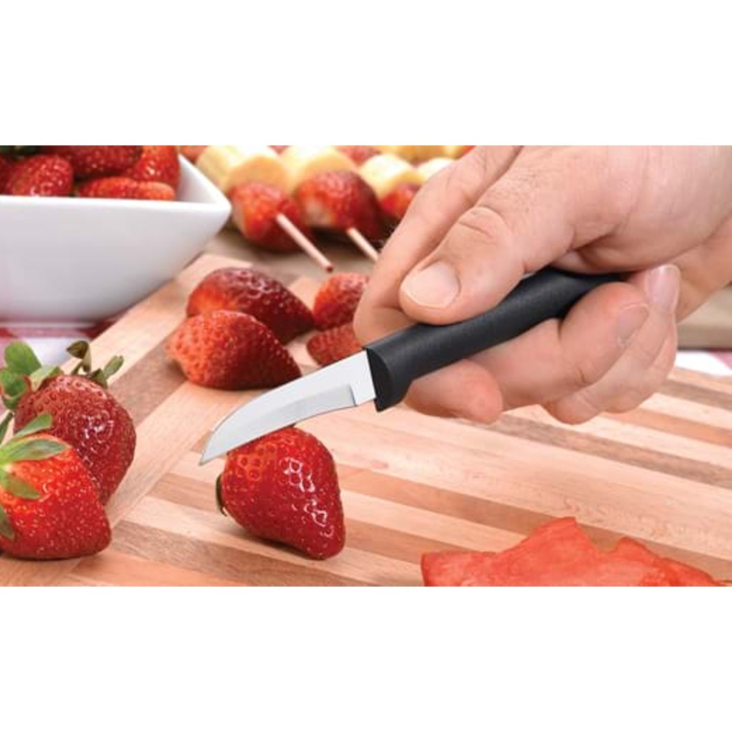 Rada Granny Parer with curved stainless steel blade and black handle slicing fresh strawberries on wooden board in kitchenware collection