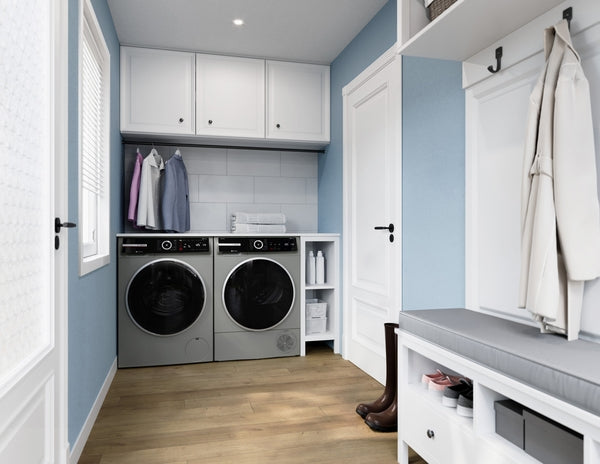 Laundry room with Bosch front load Pearl Steel washer and dryer set under white cabinets and blue walls