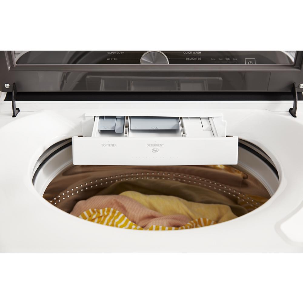 Top view of a white washer with open detergent drawer and colored clothes inside drum in appliances collection