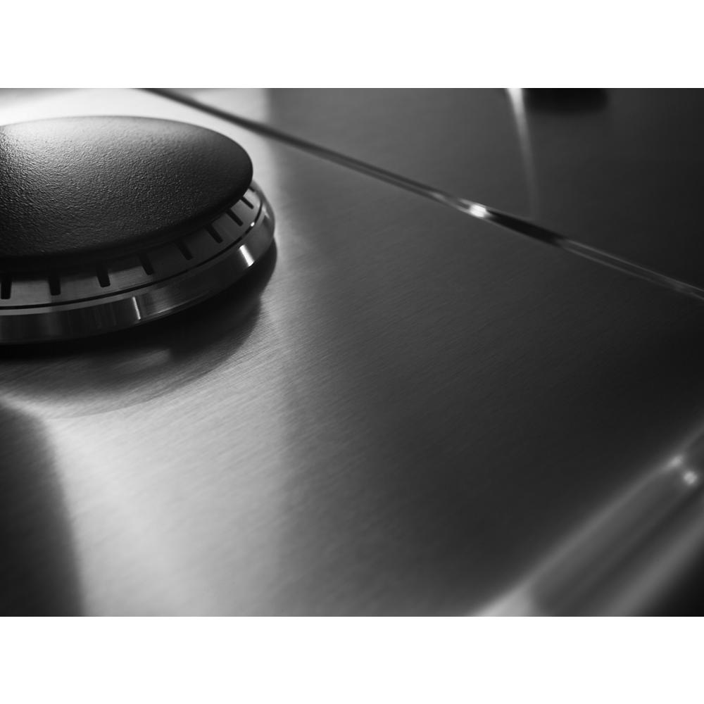 Close-up of brushed stainless steel surface and black control knob on modern gas cooktop from kitchen appliances collection