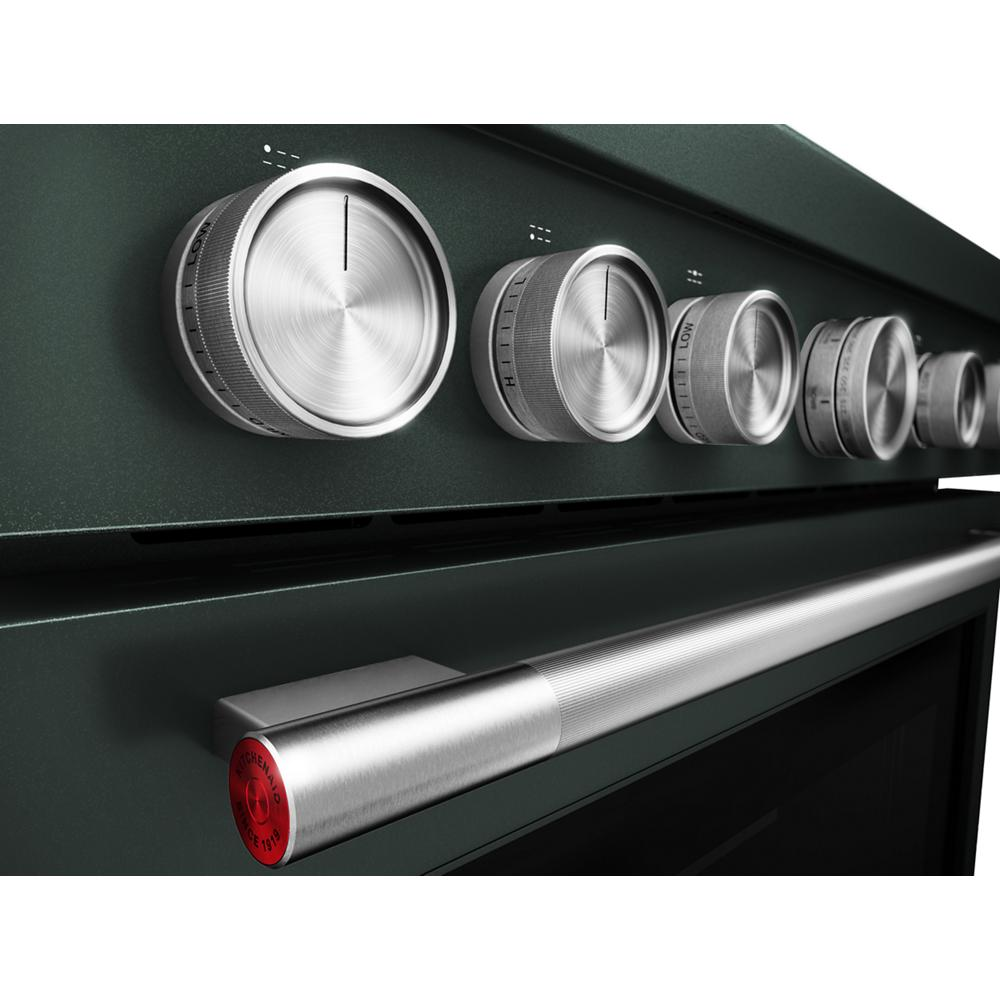 Close-up of brushed stainless steel control knobs and handle on dark green KitchenAid commercial-style dual fuel range