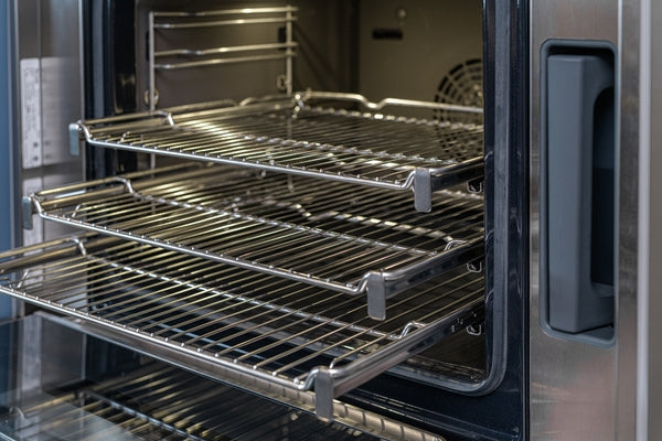 Stainless steel wire racks extended inside open single wall oven from Thermador kitchen appliance collection