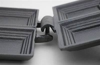Close-up of sturdy hinge on black cast iron double sandwich cooker designed for outdoor cooking and tools use
