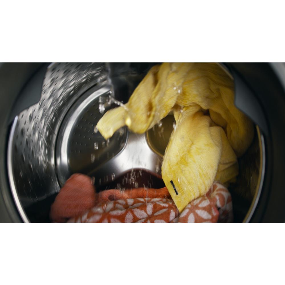 Water flowing into front load washer drum with yellow and orange towels inside from washers collection