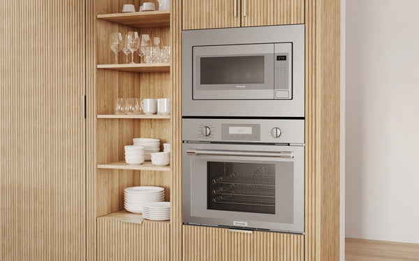 Built-in stainless steel microwave with left side door above matching built-in oven in modern kitchen cabinetry