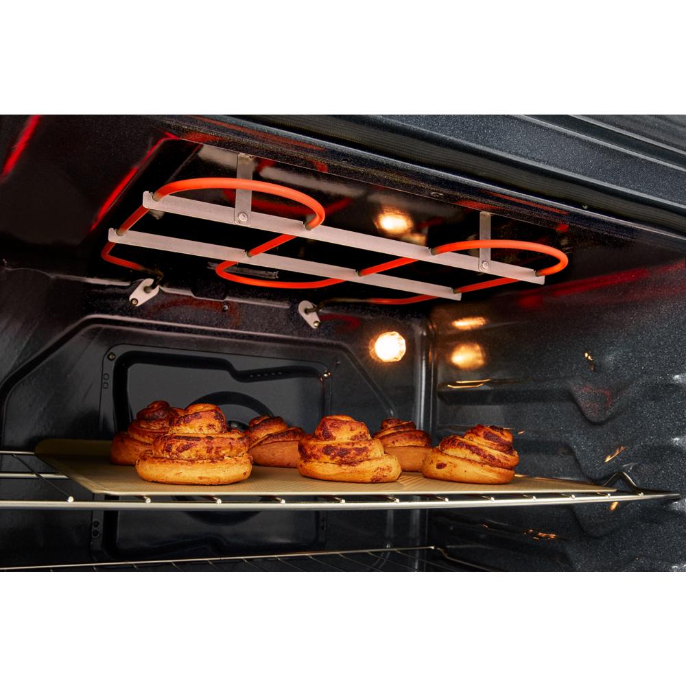 Close-up of cinnamon rolls baking on a rack beneath glowing electric heating elements inside a kitchen oven from Ranges collection