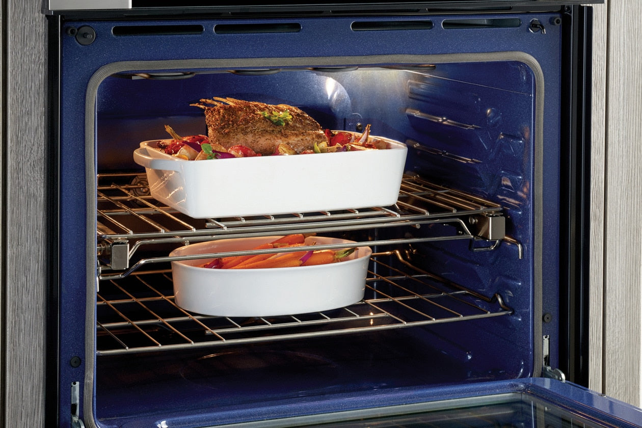 Inside view of electric double wall oven with roasted chicken and casserole dishes cooking on convection racks